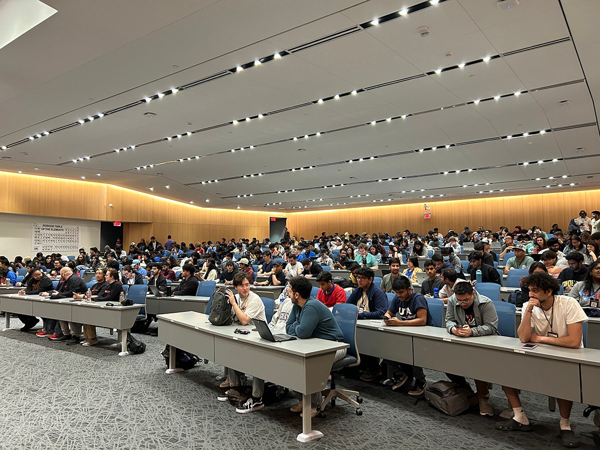 Students sitting at tables in a lecture hall - opens in a new tab